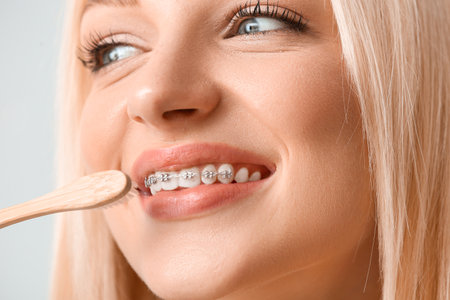 Young woman with dental braces and wooden toothbrush, closeup