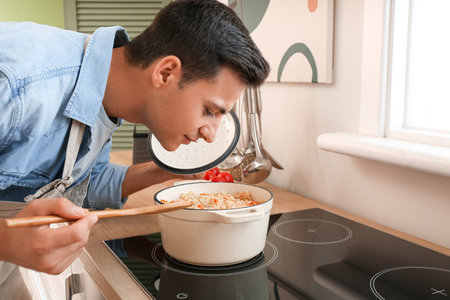 Young man cooking rice in the kitchenの写真素材
