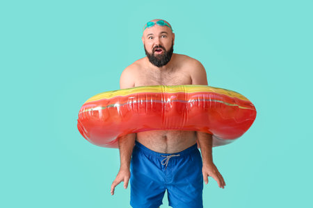Overweight man with inflatable ring on color backgroundの写真素材