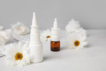 Nasal drops with pills, flowers and tissues on table near gray wall. Seasonal allergy conceptの写真素材