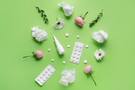 Nasal drops with pills, flowers and tissues on green background. Seasonal allergy concept