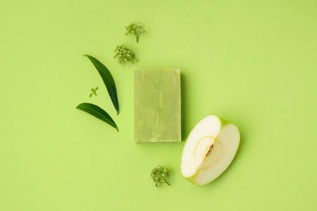Composition with natural soap bar, piece of apple and plant leaves on color backgroundの写真素材