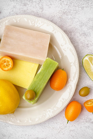 Plate with natural soap bars, citrus fruits and olives on light background, closeupの写真素材