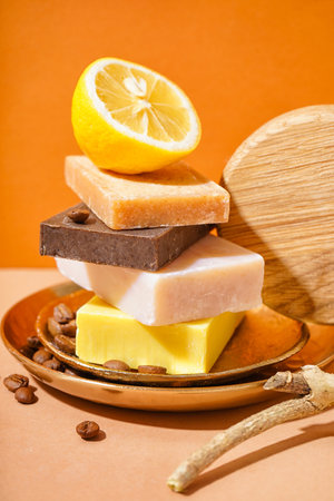 Composition with natural soap bars, lemon and coffee beans on color background, closeup
