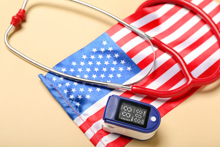 Stethoscope with pulse oximeter and USA flag on beige background, closeupの写真素材