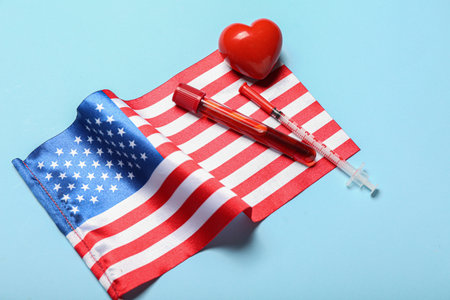Test tube, heart, syringe and USA flag on blue background, closeupの写真素材