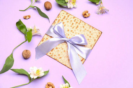 Composition with Jewish flatbread matza for Passover, walnuts and alstroemeria flowers on color...