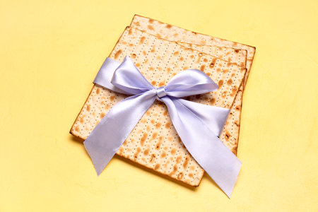 Jewish flatbread matza for Passover tied with ribbon on yellow background