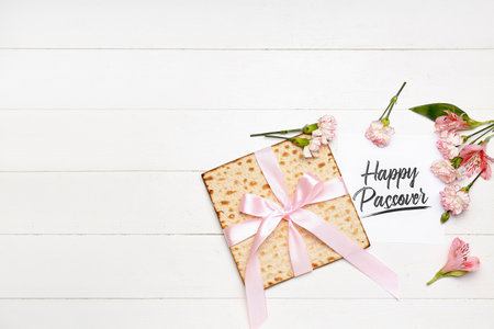 Card with text HAPPY PASSOVER, flatbread matza and alstroemeria flowers on light wooden backgroundの写真素材
