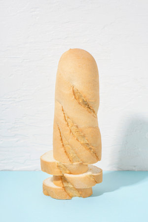 Fresh sliced baguette on blue table near white wall