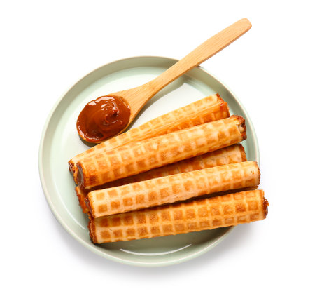 Plate of delicious wafer rolls with boiled condensed milk isolated on white backgroundの写真素材