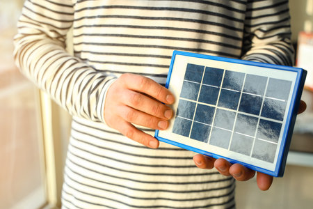 Young man with portable solar panel at home, closeup