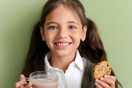 Little girl with tasty chocolate milk and cookie on color backgroundの写真素材