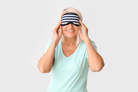 Mature woman in sleep mask on light backgroundの写真素材