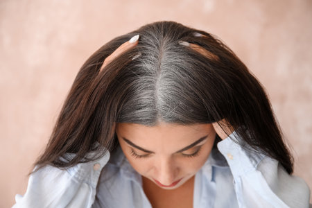 Stressed woman with graying hair on color backgroundの写真素材