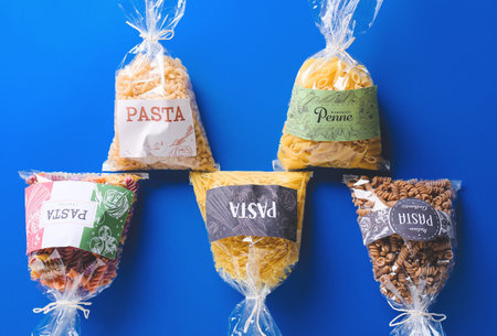 Bags with uncooked pasta on color backgroundの写真素材