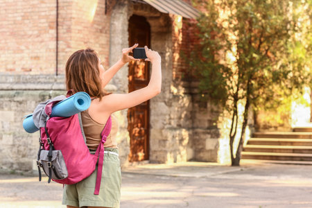 Female tourist taking photo on city streetの写真素材