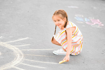 Little girl drawing with chalk on asphaltの写真素材