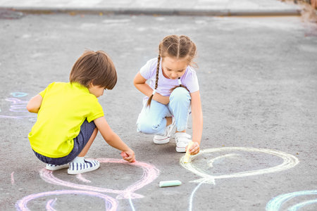Little children drawing with chalk on asphaltの写真素材