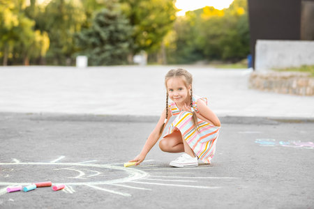 Little girl drawing with chalk on asphaltの写真素材