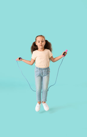 Cute little girl jumping rope against color backgroundの写真素材