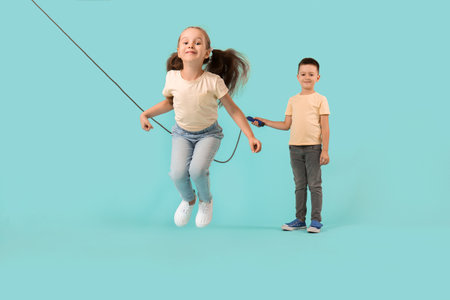 Cute little children jumping rope against color backgroundの写真素材