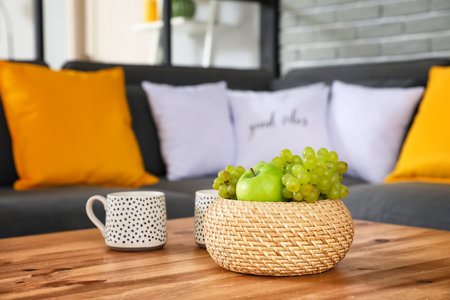 Wicker basket with grapes on table in living roomの写真素材