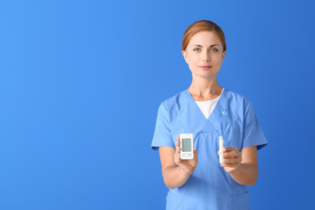 Doctor with digital glucometer and lancet pen on color background. Diabetes conceptの写真素材