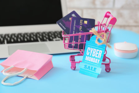 Shopping bag, cart, credit cards, laptop and tag with text CYBER MONDAY SALE on tableの写真素材