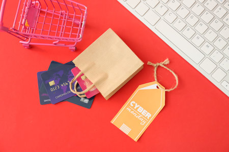 Shopping bag with credit cards, trolley, computer keyboard and tag with text CYBER MONDAY on color backgroundの写真素材