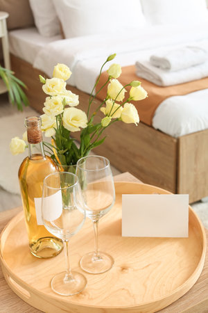 Tray with bottle of wine and glasses on table in hotel honeymoon roomの写真素材
