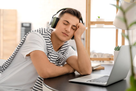 Sleepy young man listening to music at home