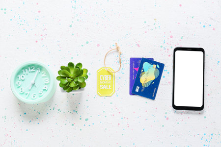 Alarm clock with credit cards, mobile phone and shopping tag with text CYBER MONDAY SALE on white backgroundの写真素材