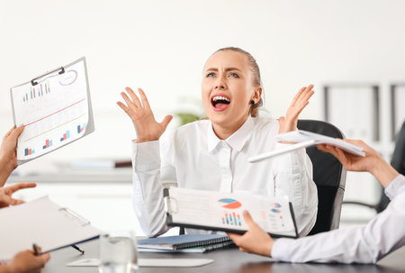 Stressed woman with headache and noisy people in officeの写真素材