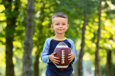Little boy playing American football outdoorsの写真素材