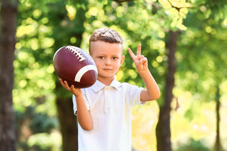 Little boy playing American football outdoors