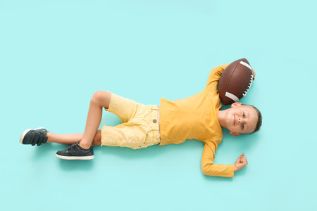 Little boy with rugby ball on color background, top viewの写真素材