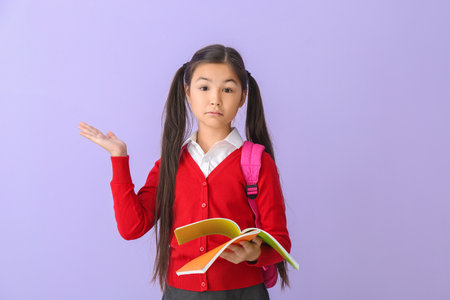 Troubled little schoolgirl with copybook on color background