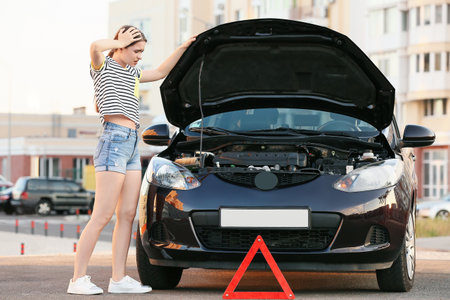 Emergency stop sign and stressed woman near broken car outdoors