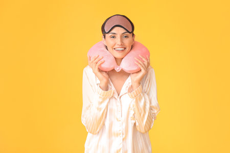 Young woman with sleep mask and neck pillow on color backgroundの写真素材