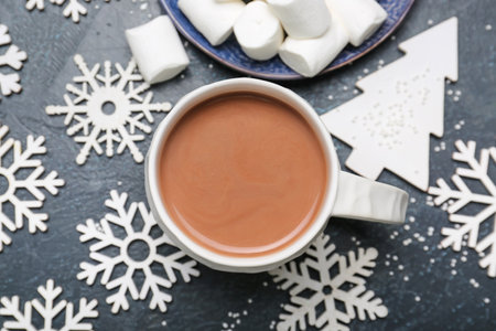 Cup of hot cacao drink with marshmallows and Christmas decorations on dark background