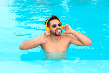Young man listening to music in swimming pool