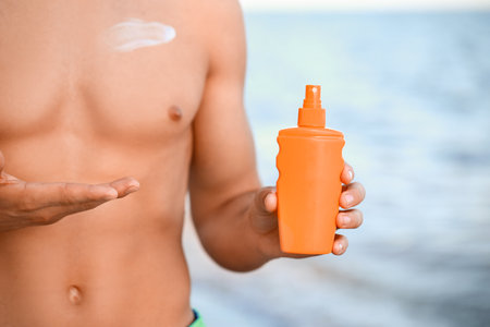 Handsome young man with sunscreen cream on sea beach, closeupの写真素材