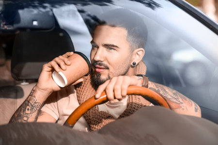 Handsome man with coffee to-go near modern car