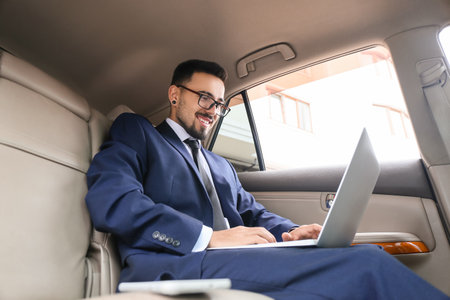 Successful businessman with laptop in modern car
