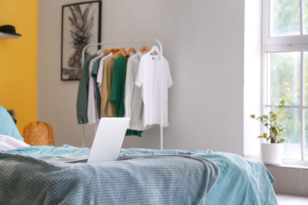 Modern laptop on bed in interior of comfortable bedroomの写真素材