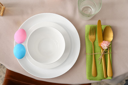 Set of plates and cutlery with Easter eggs and flower on tableの写真素材