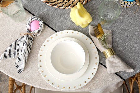 Easter egg wrapped in bunny ears napkin and set of plates on festive table