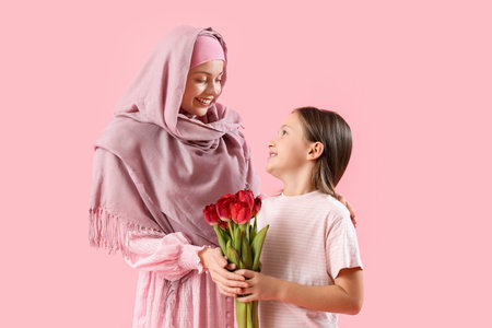 Little girl with tulips and her Muslim mother on pink backgroundの写真素材