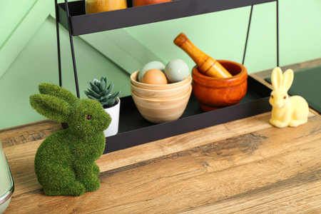 Easter bunnies and painted eggs on kitchen counter near green wall
